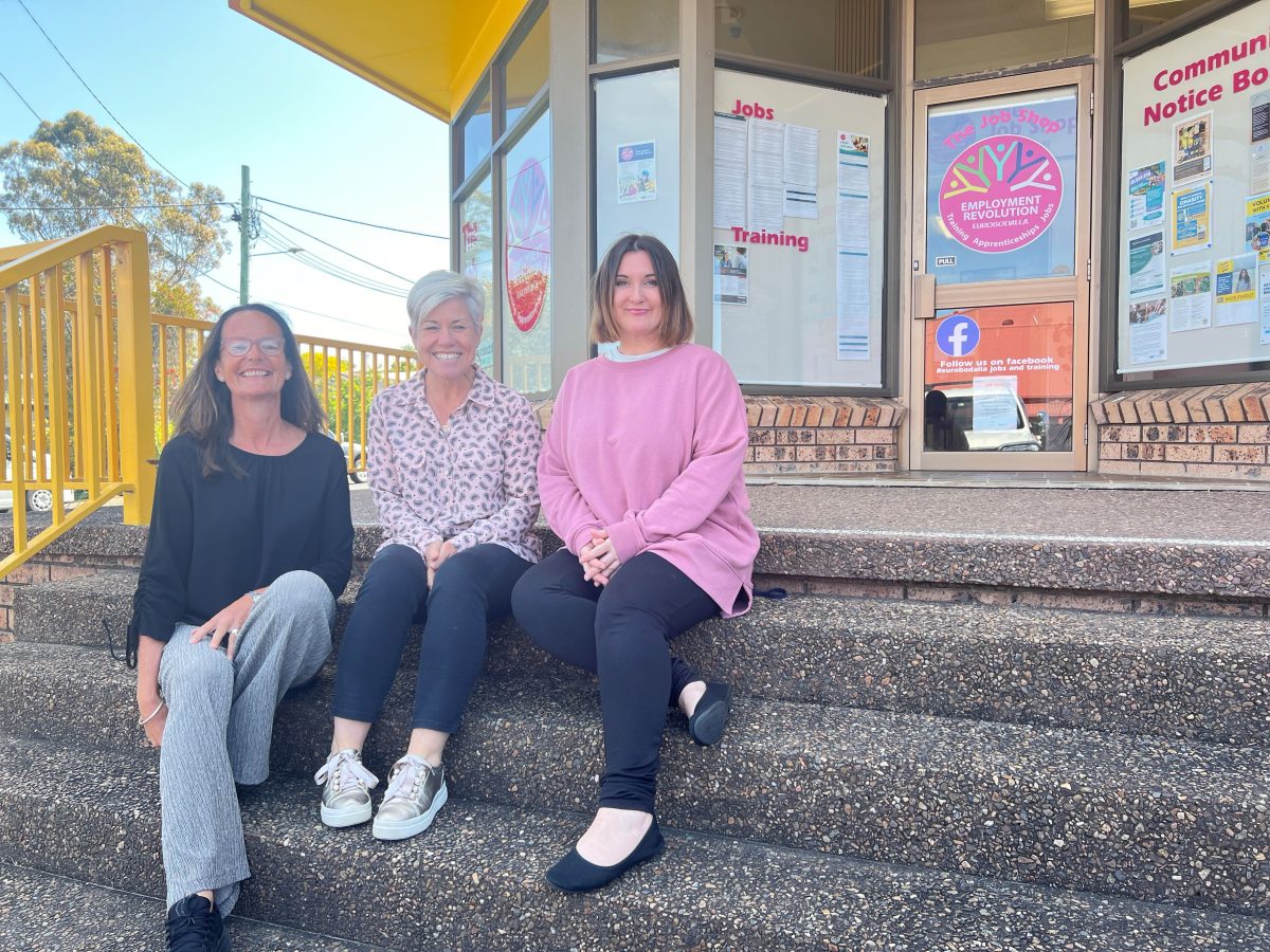 Three people sitting on concrete steps outside a building