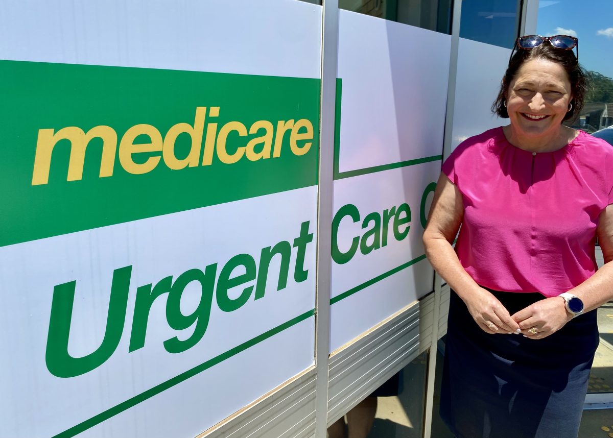 A smiling woman standing next to a sign