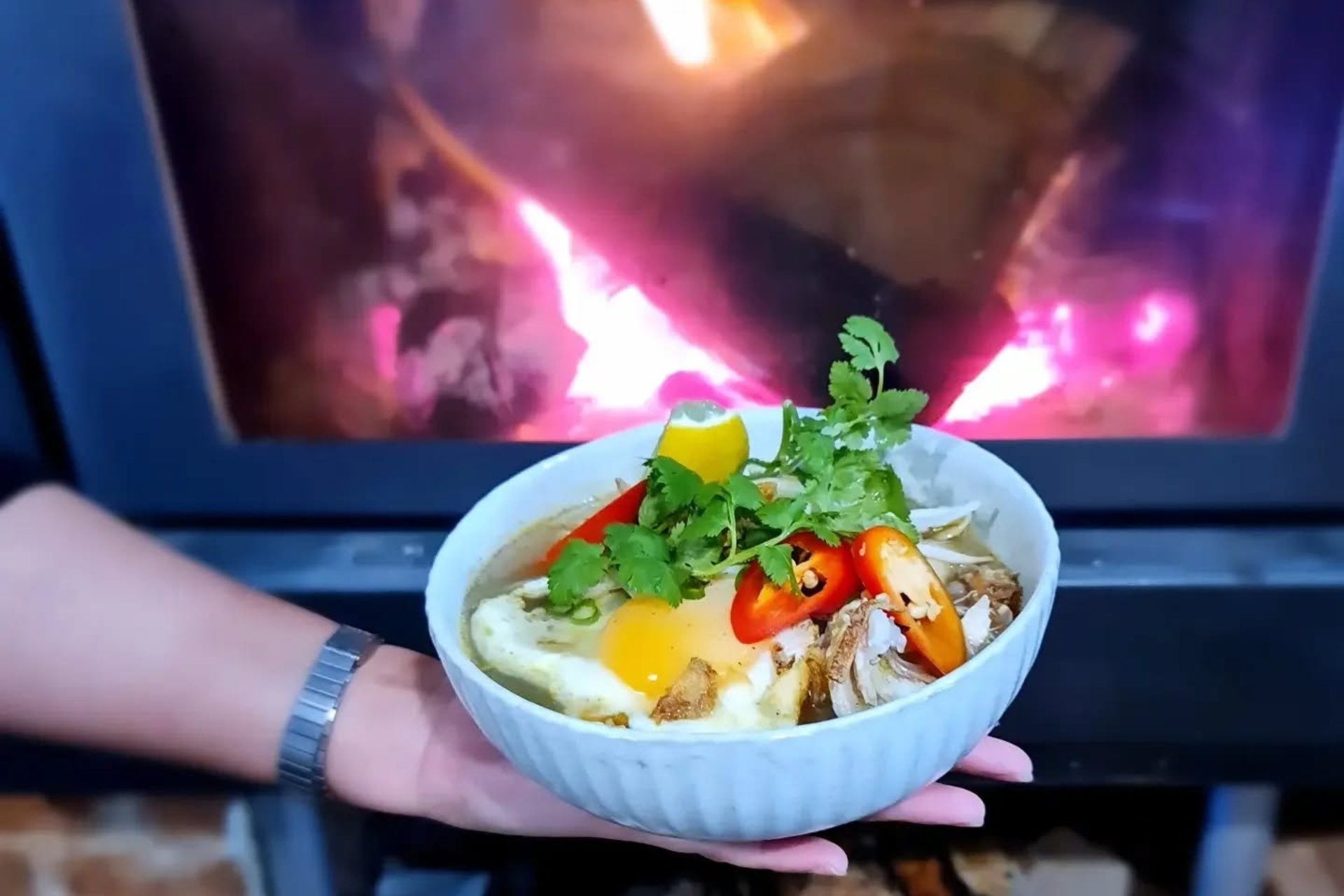 A bowl of soup in front of a fireplace.