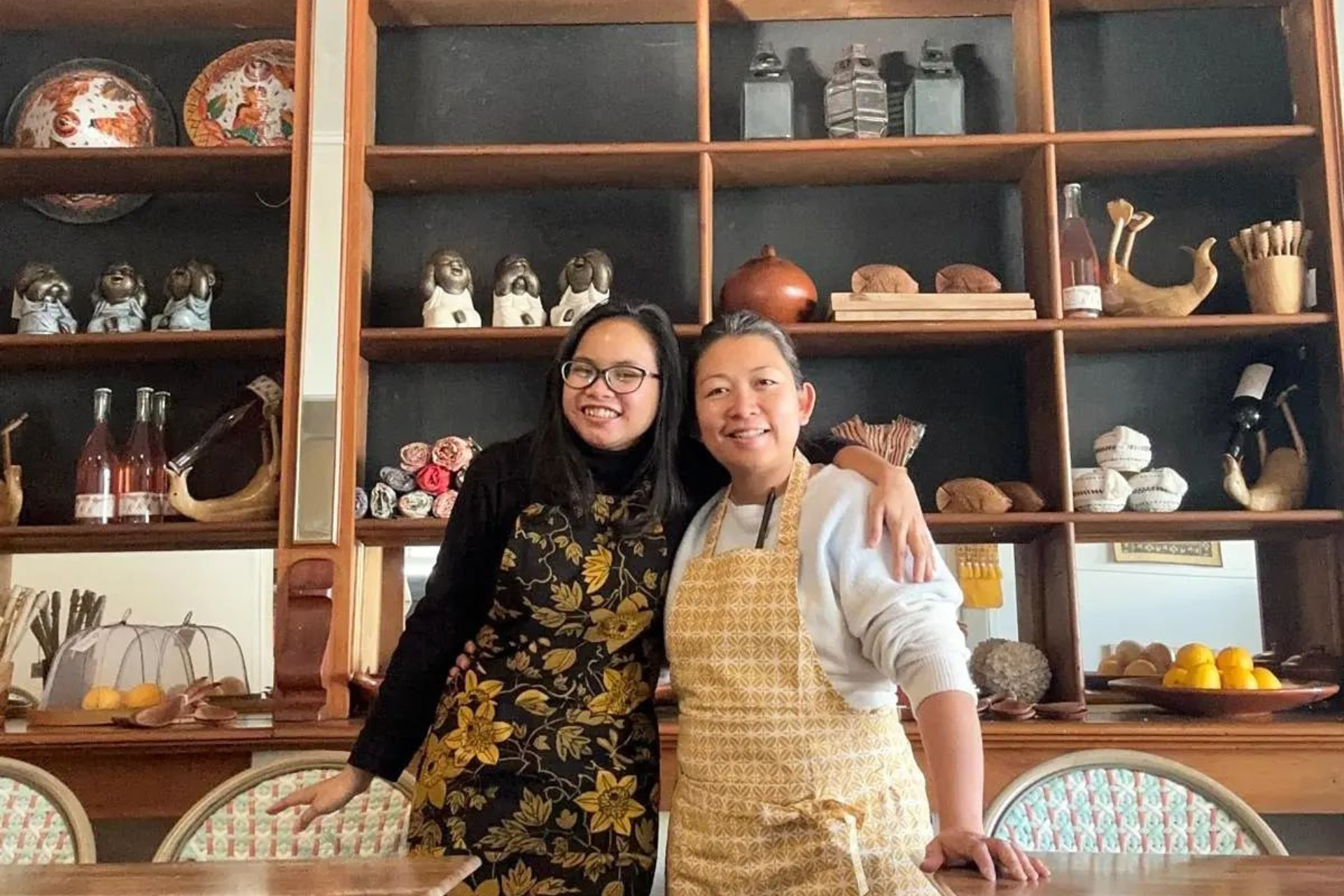 Daniar with Anodya smiling in front of decorated shelves.