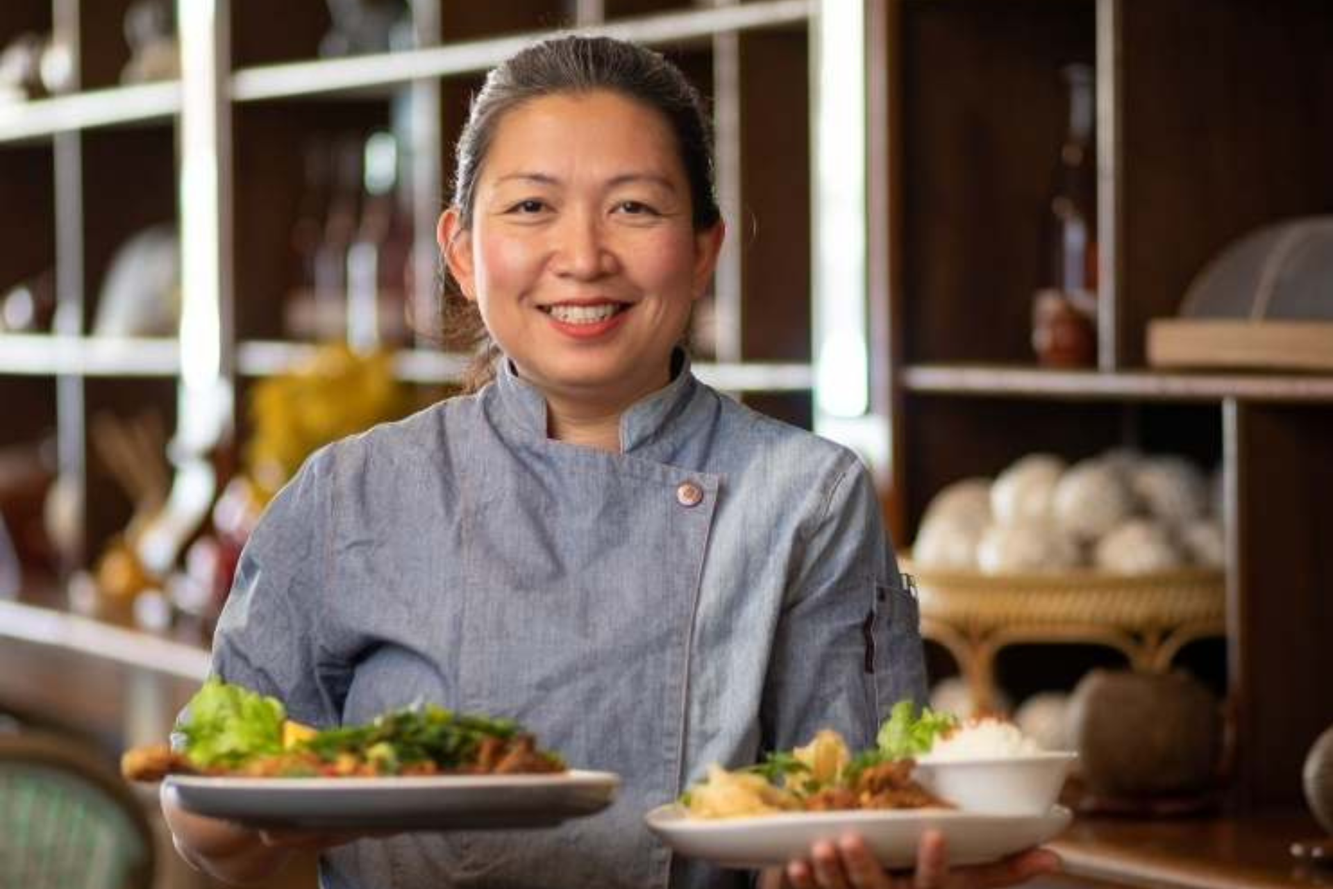 Daniar Robinson smiling holding plates of Indonesian food.