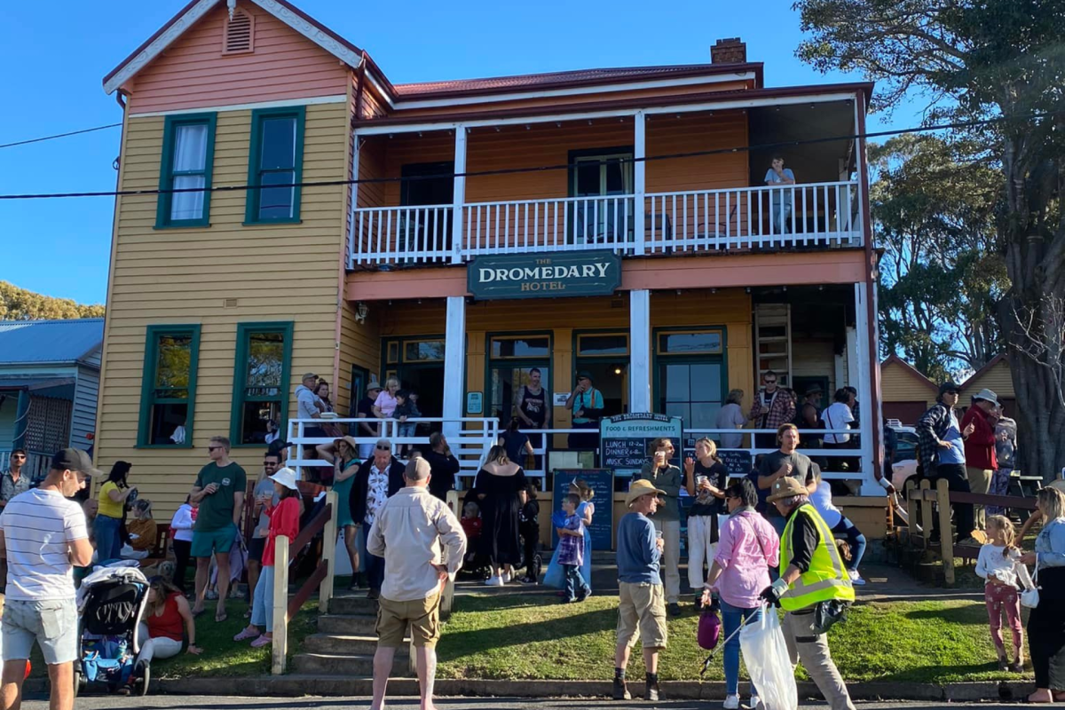 Two story weatherboard building with a crowd of people.