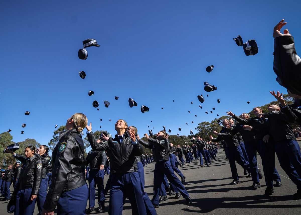 police academy graduates throwing their hats into the air