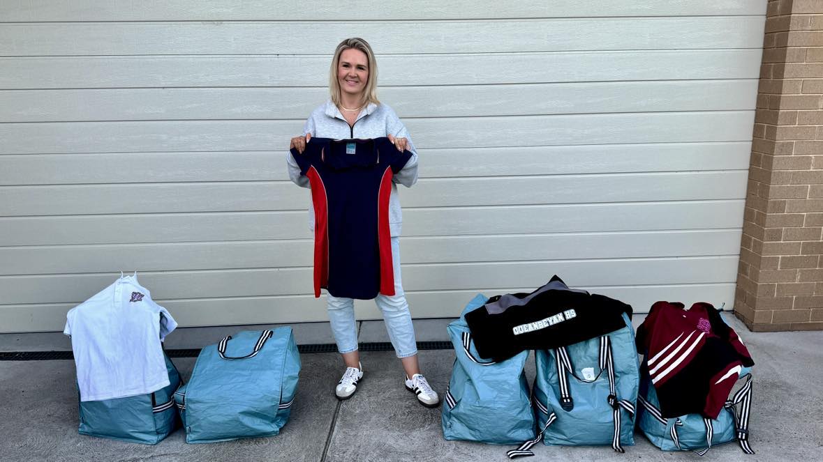 A woman holding a shirt in front of donated bags of clothes