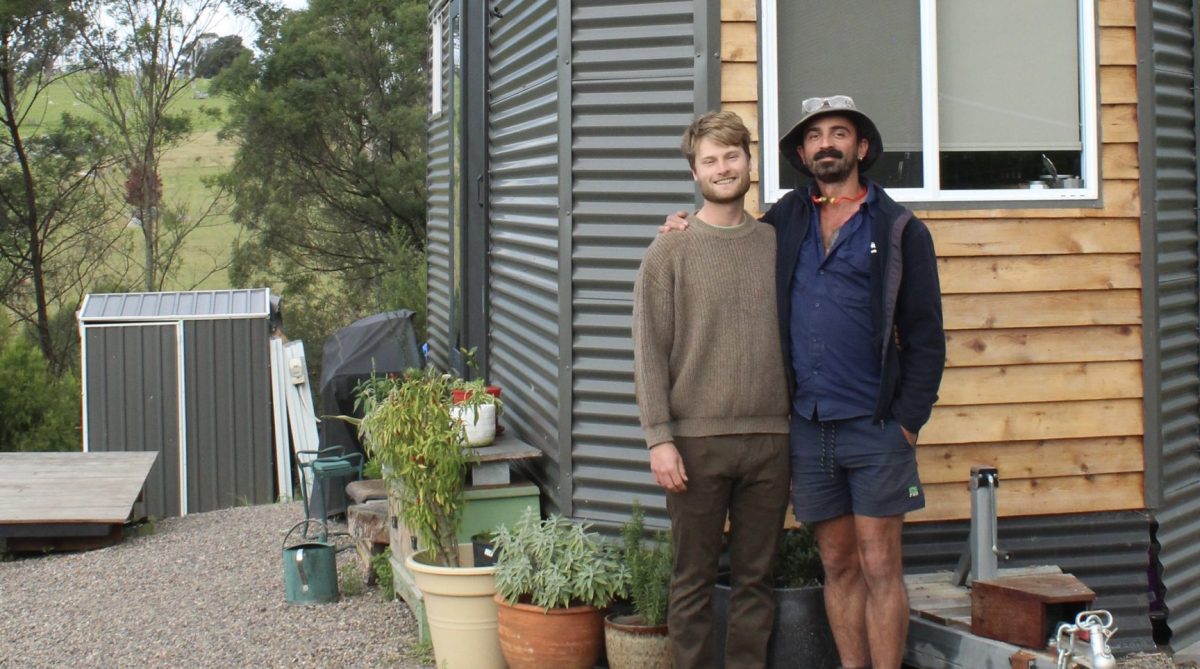 two men standing next to a small house