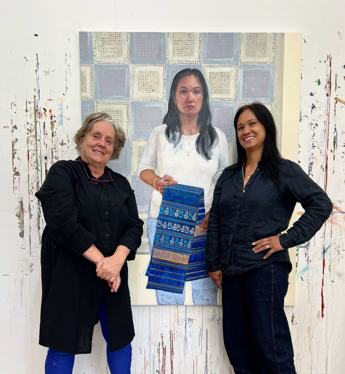 Two women standing in front of a portrait