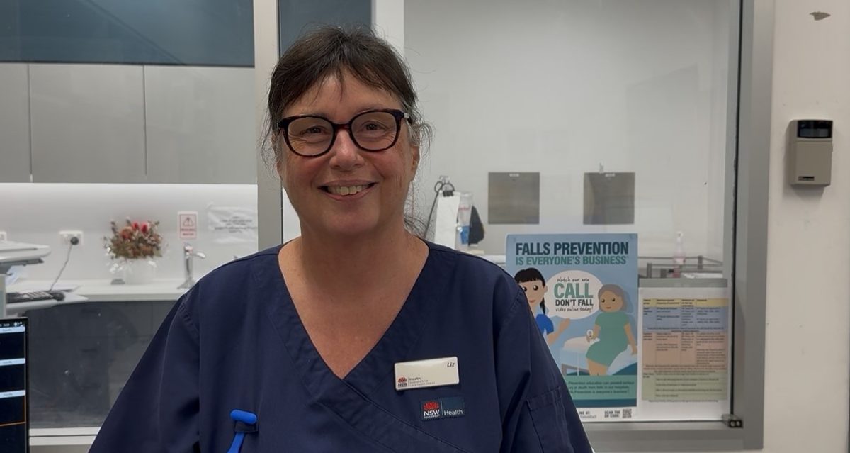 A woman in scrubs wearing glasses and with her hair tied back