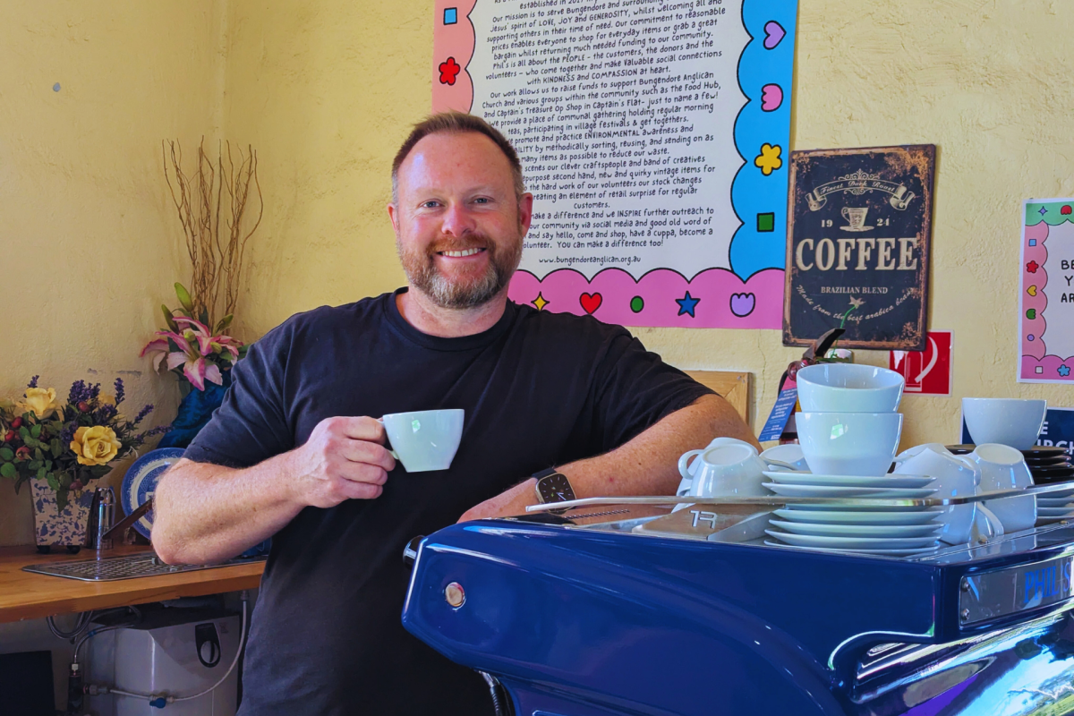 Make holds cup of coffee in front of coffee machine