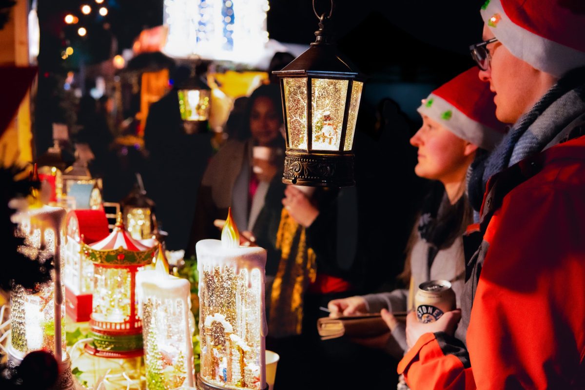 two people wearing santa hats looking at a stall selling snow globes