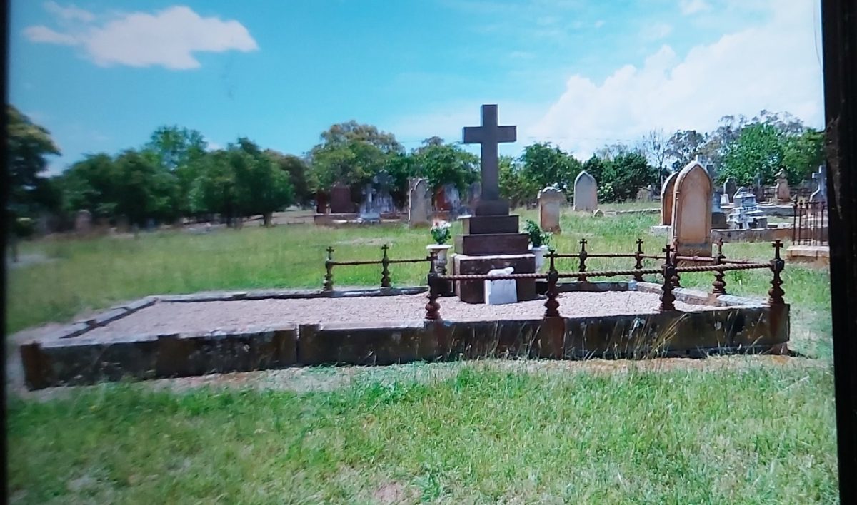 A family plot with fencing around part of it and a large cross