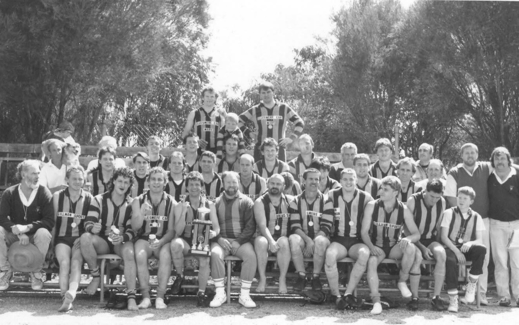 The Hawks premiership team from 1990. Bob Stephens is on the right, third row, Gavin Halder is second from the right end on the second row. Steve Armstrong is in the front row holding a trophy and Wendell Rosewarne is on the left, with his dog Monty.