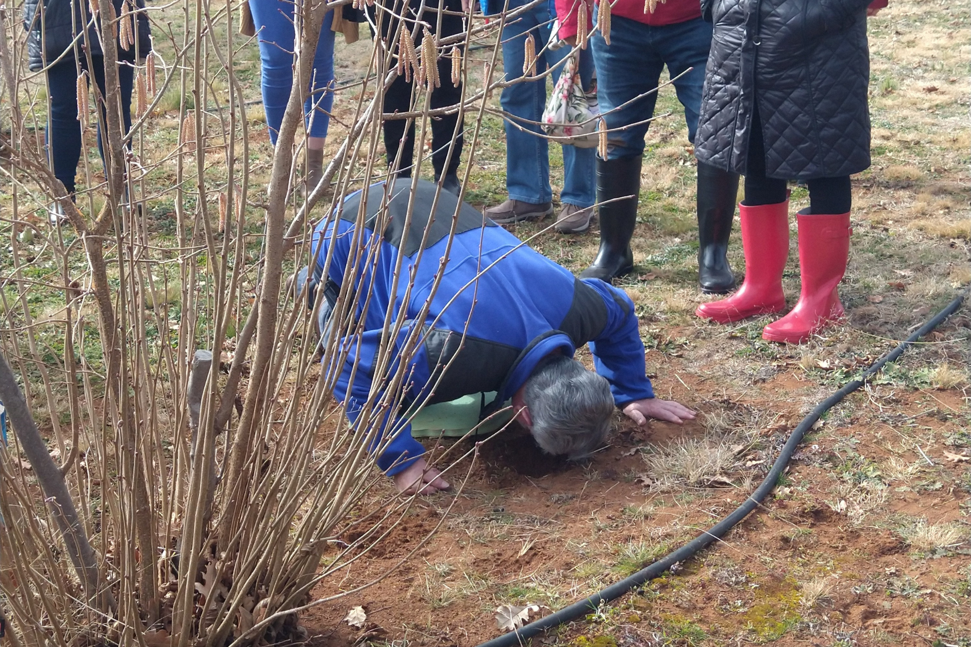 Man on knees smelling the soil.