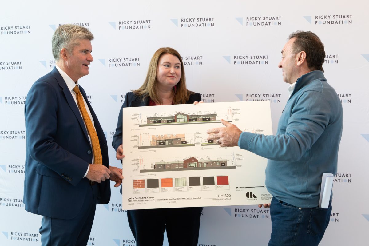 Three people talking while looking at a large print of building plans