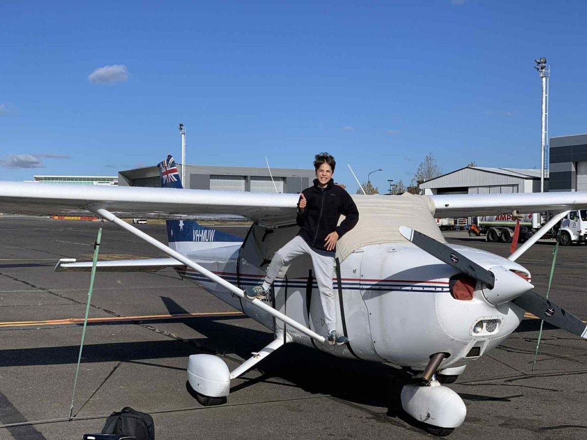 A teenage boy standing on a plane's wing