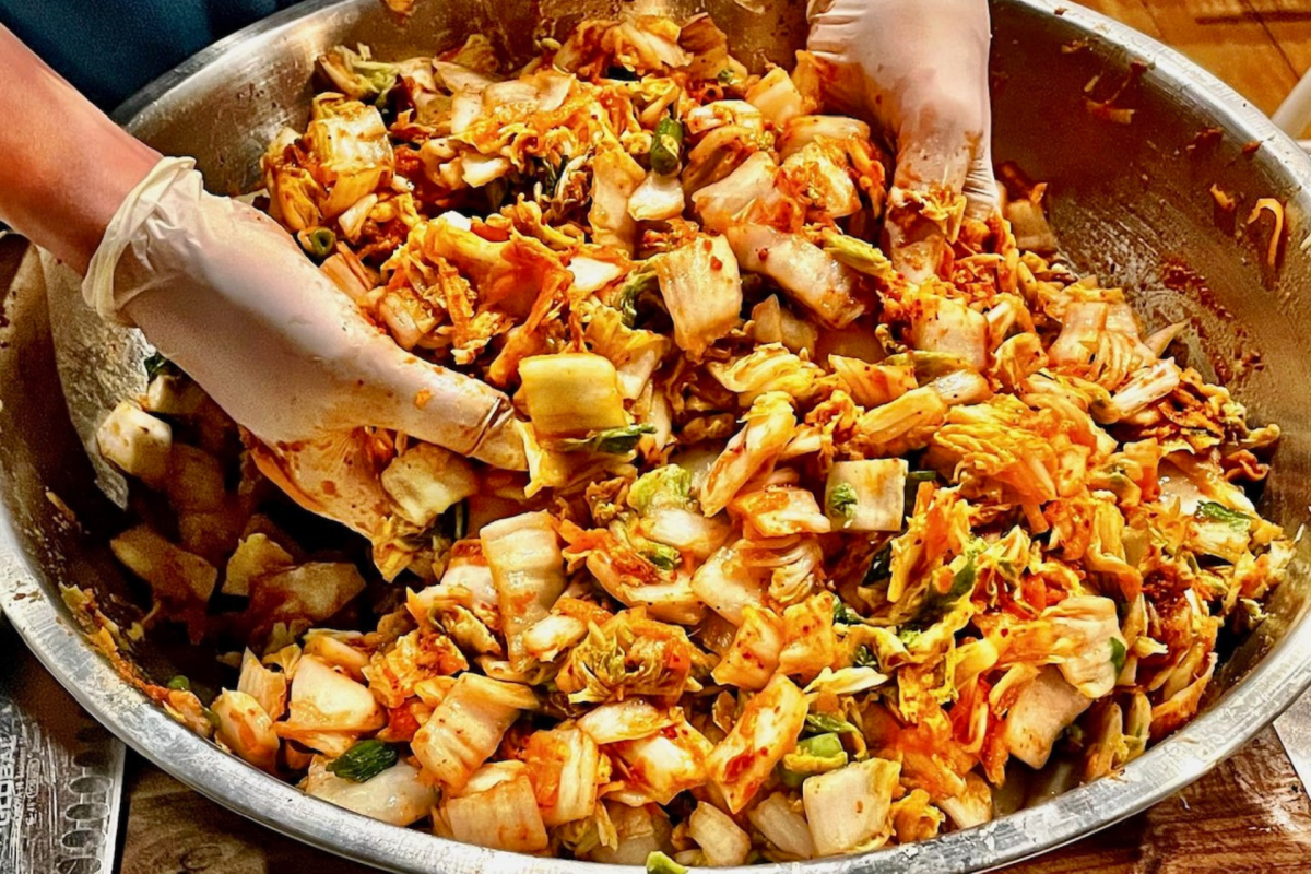 hands mixing chilli cabbage into kimchi