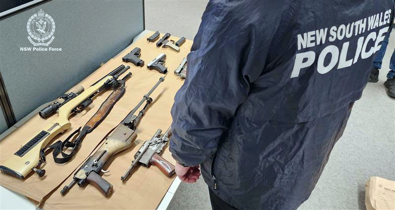 Police examine items allegedly found during a raid at Wamboin on 11 July.