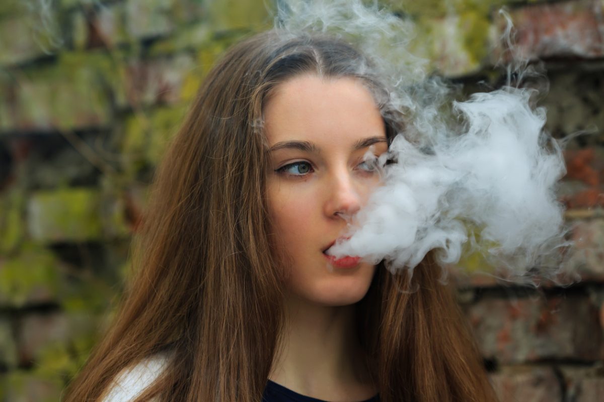 teenager exhaling vapour from an electronic cigarette