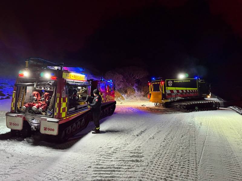 Two emergency vehicles in the snow at night