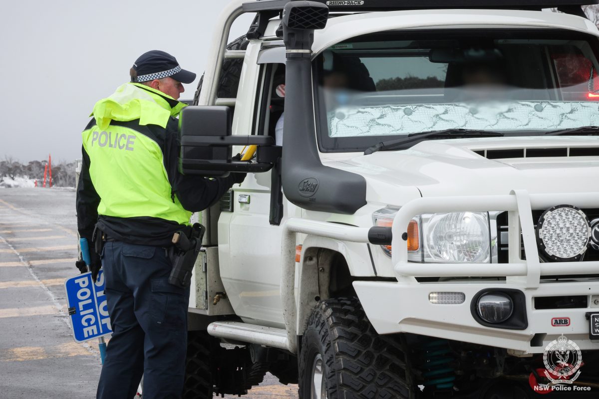 A police officer talking to someone sitting in a ute