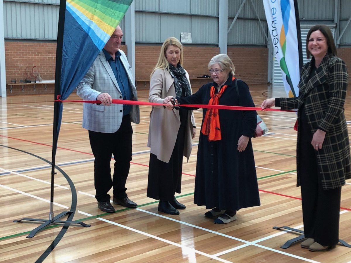 people cutting a ribbon at the opening of an upgraded indoor sports stadium