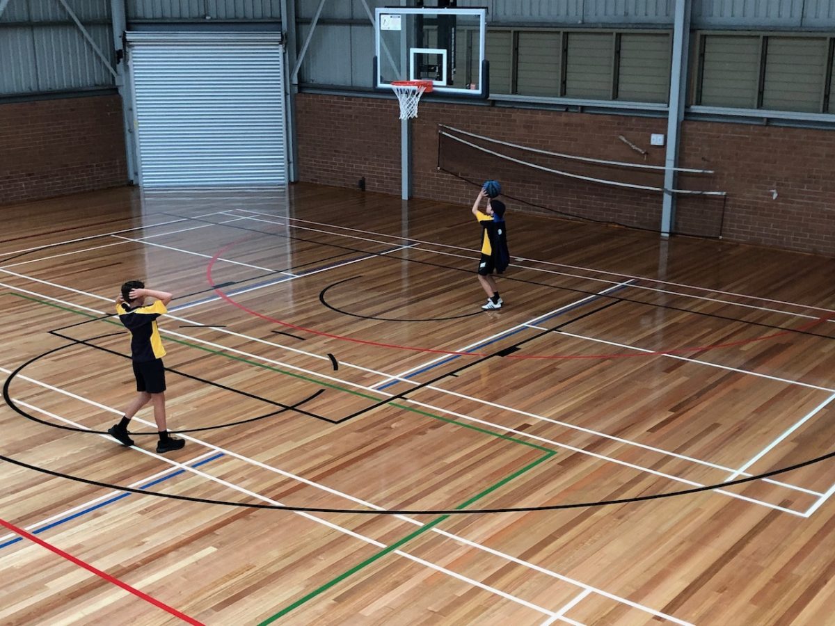 kids shooting hoops at an indoor sports stadium