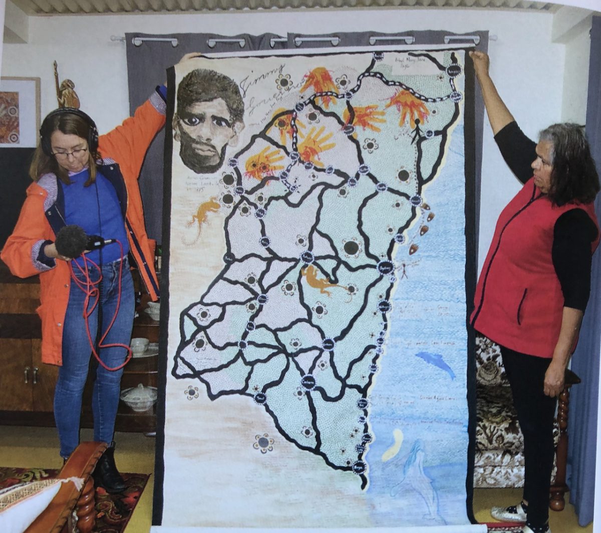 Aunty Loretta Parsley (right) shows her painting of Jimmy Governor's life, journey and family with podcast producer Kaitlyn Sawrey.