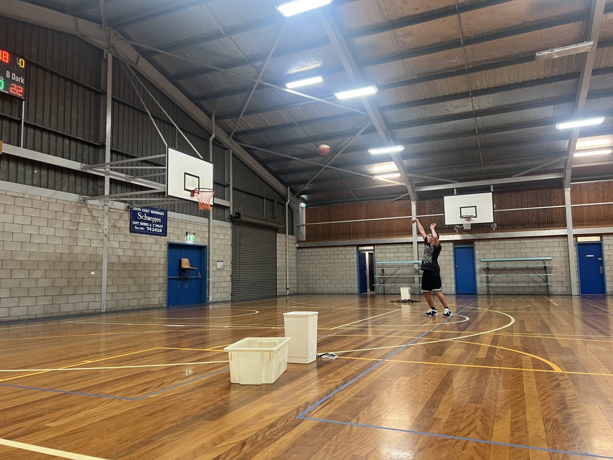 A man throwing a basketball inside an indoor stadium