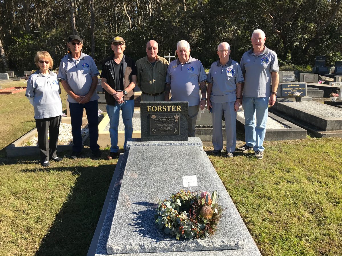 A group of people standing behind a restored grave