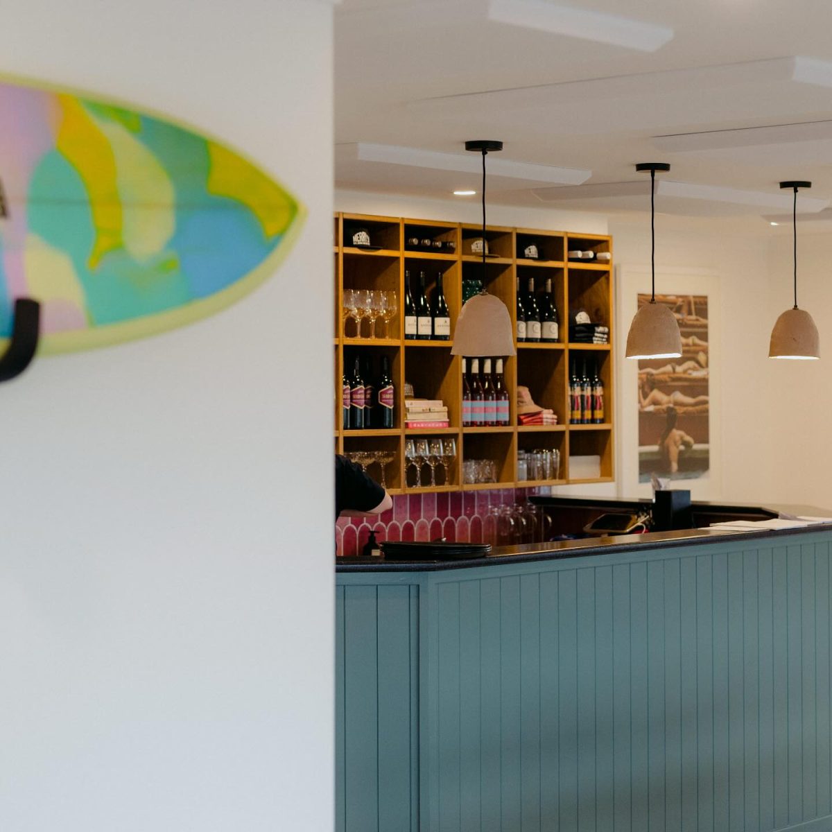 Interior of a restaurant with part of a surfboard painting showing on the wall