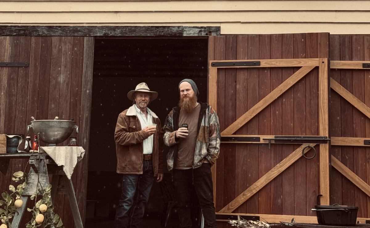 two men standing outside a timber building