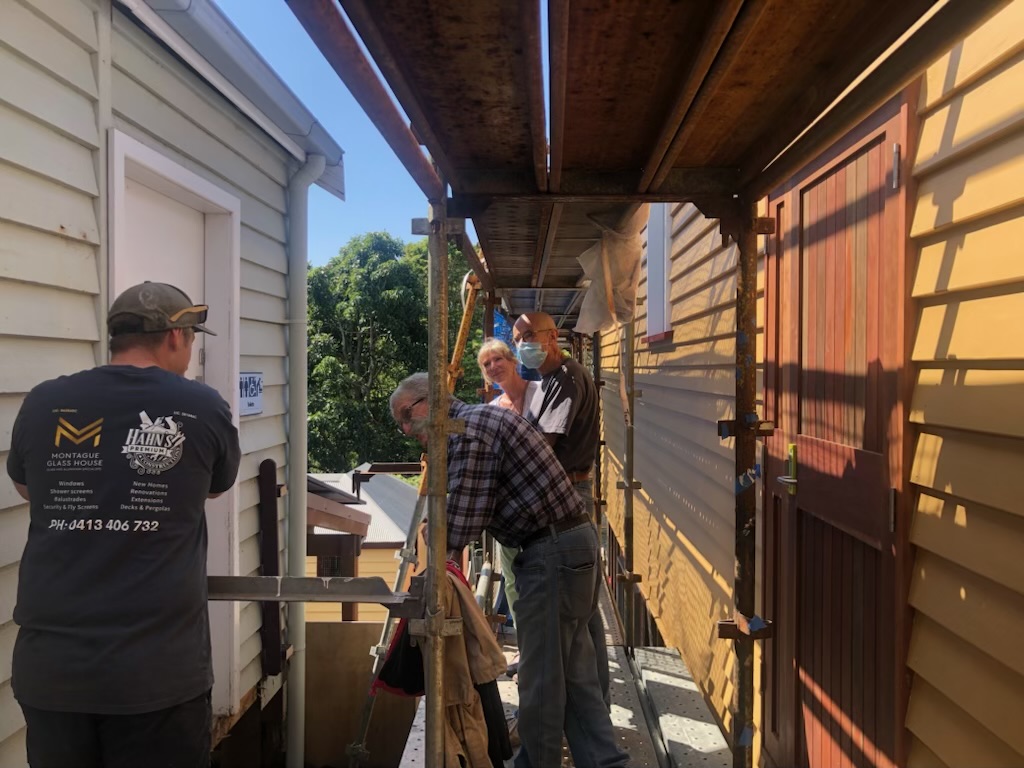 A builder and some committee members on-site at the Central Tilba halls.