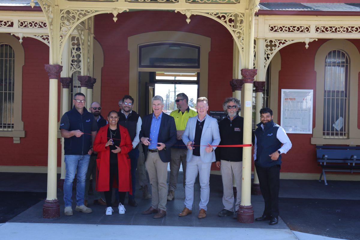 A group of people standing in two rows for a ribbon-cutting ceremony at a train station