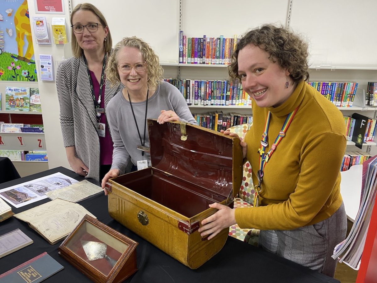 three women showing an old trunk