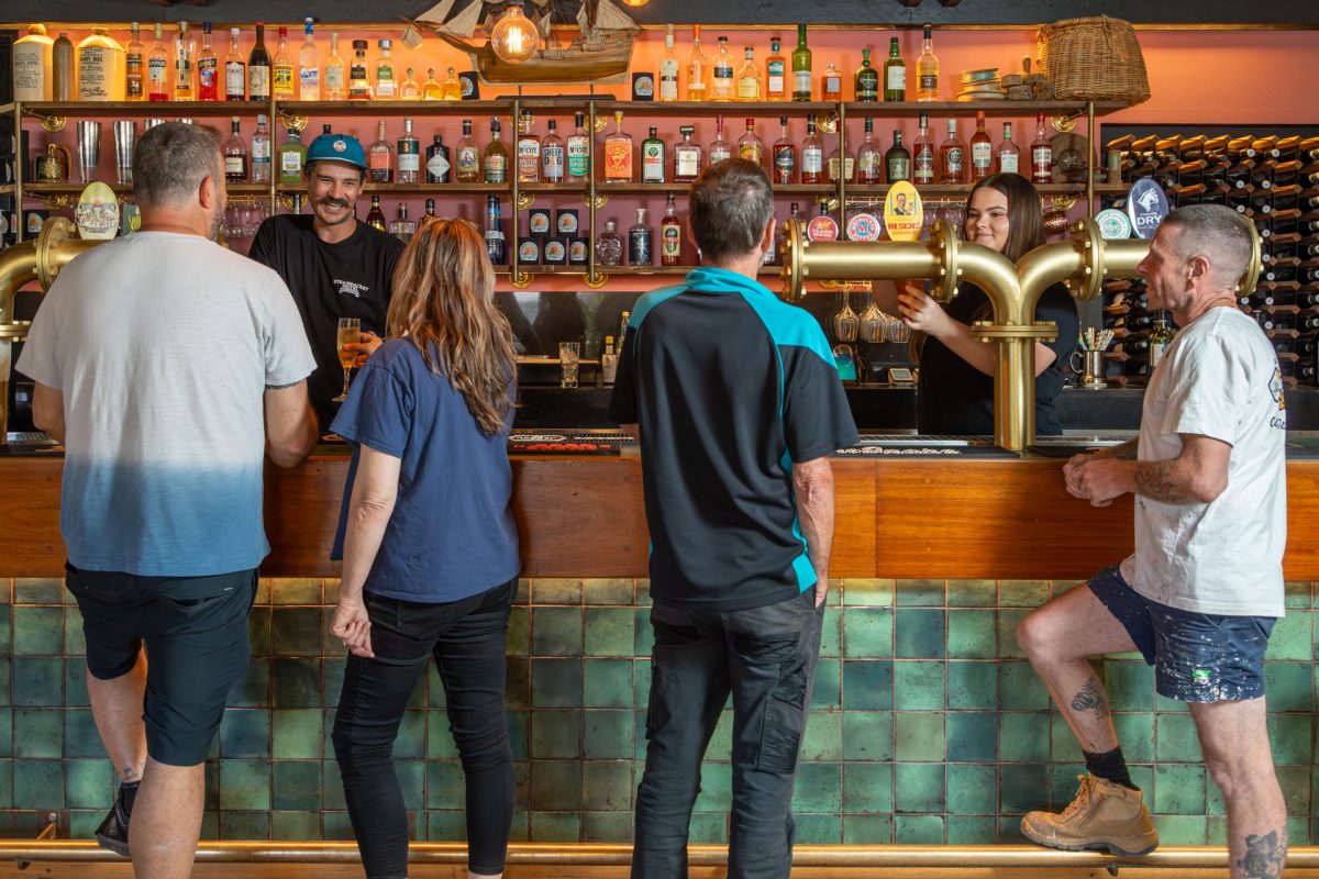 People standing at a bar waiting to be served drinks