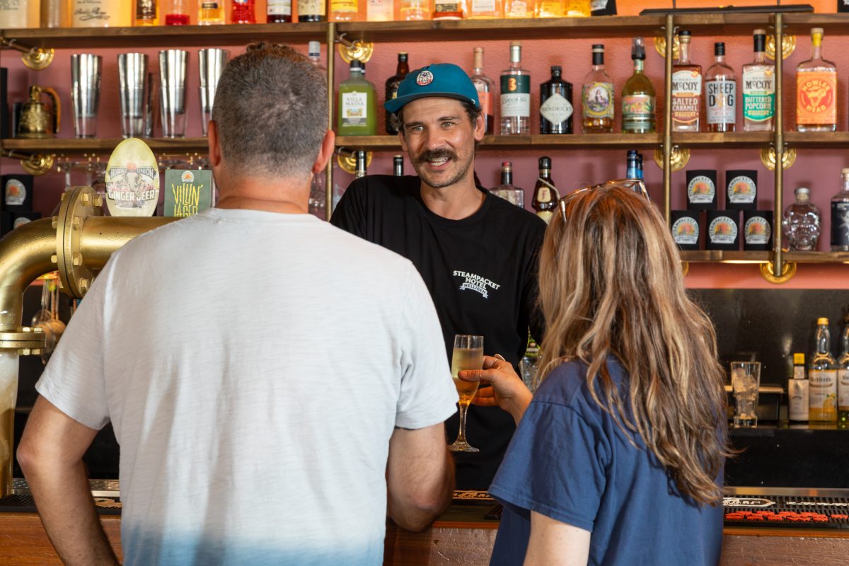 People standing at a bar waiting to be served drinks