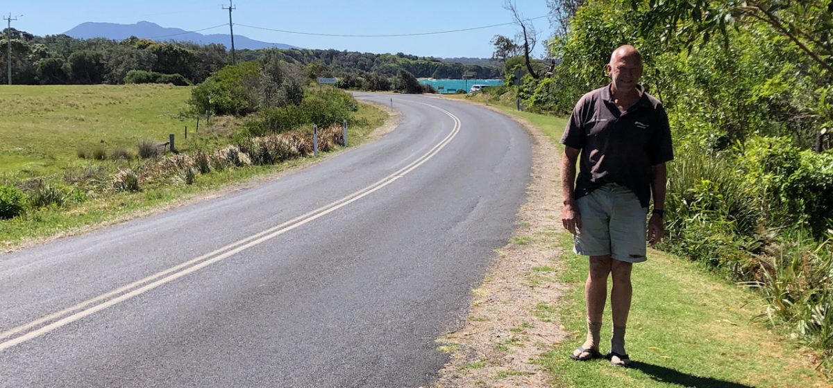 man standing next to a curving road