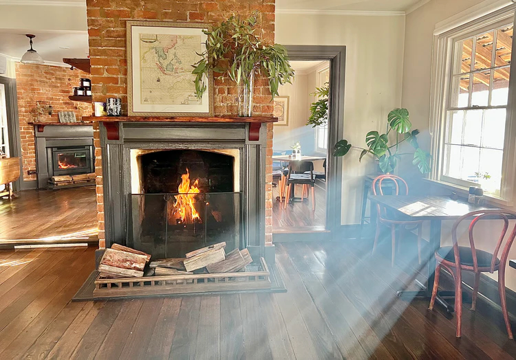 A shaft of sunlight enters a room with a roaring fire