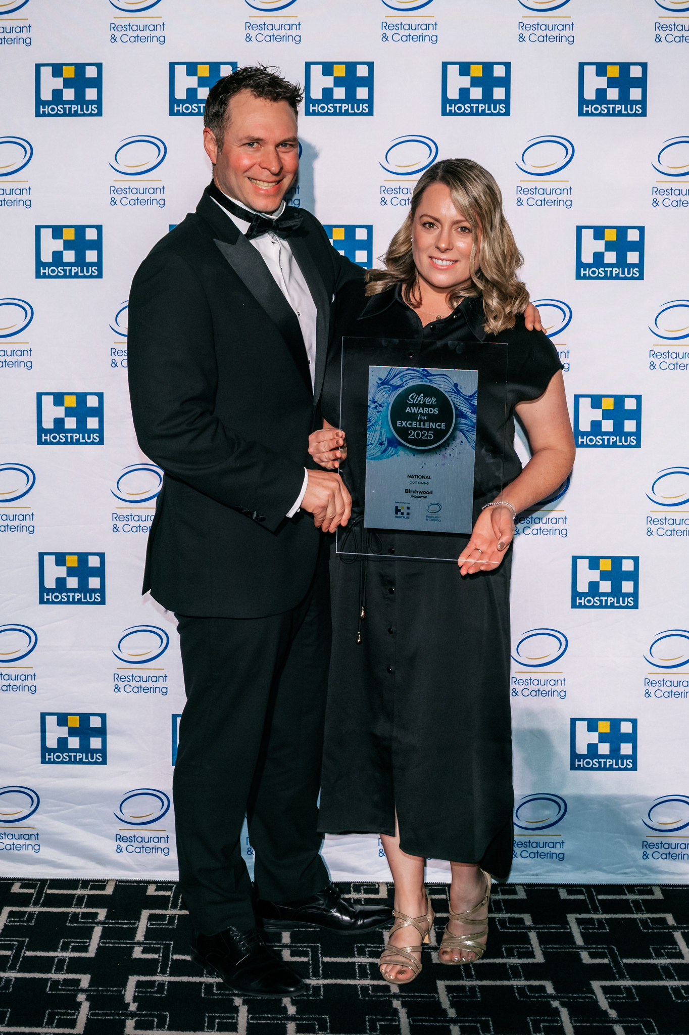 Man and woman hold an award plaque