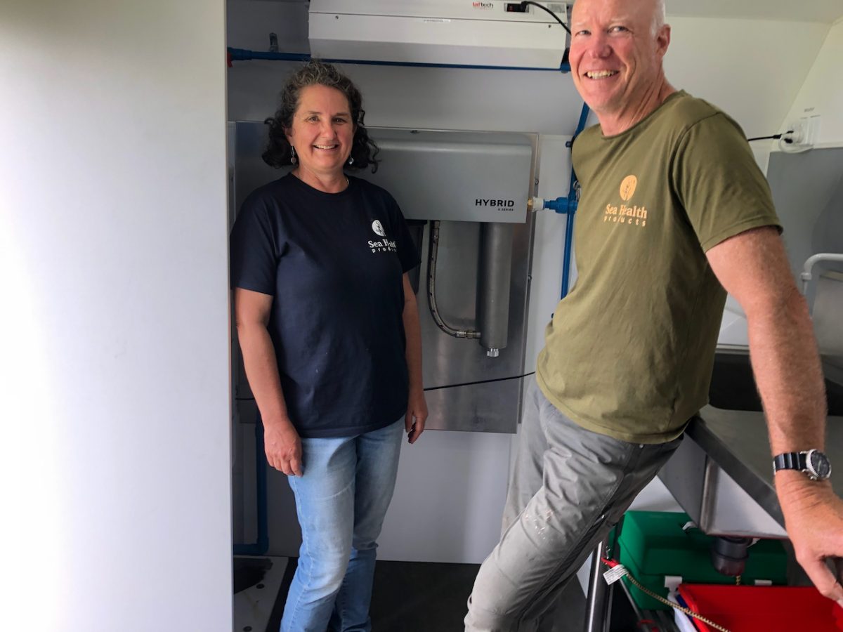 A smiling woman and man in a mobile seaweed hatchery