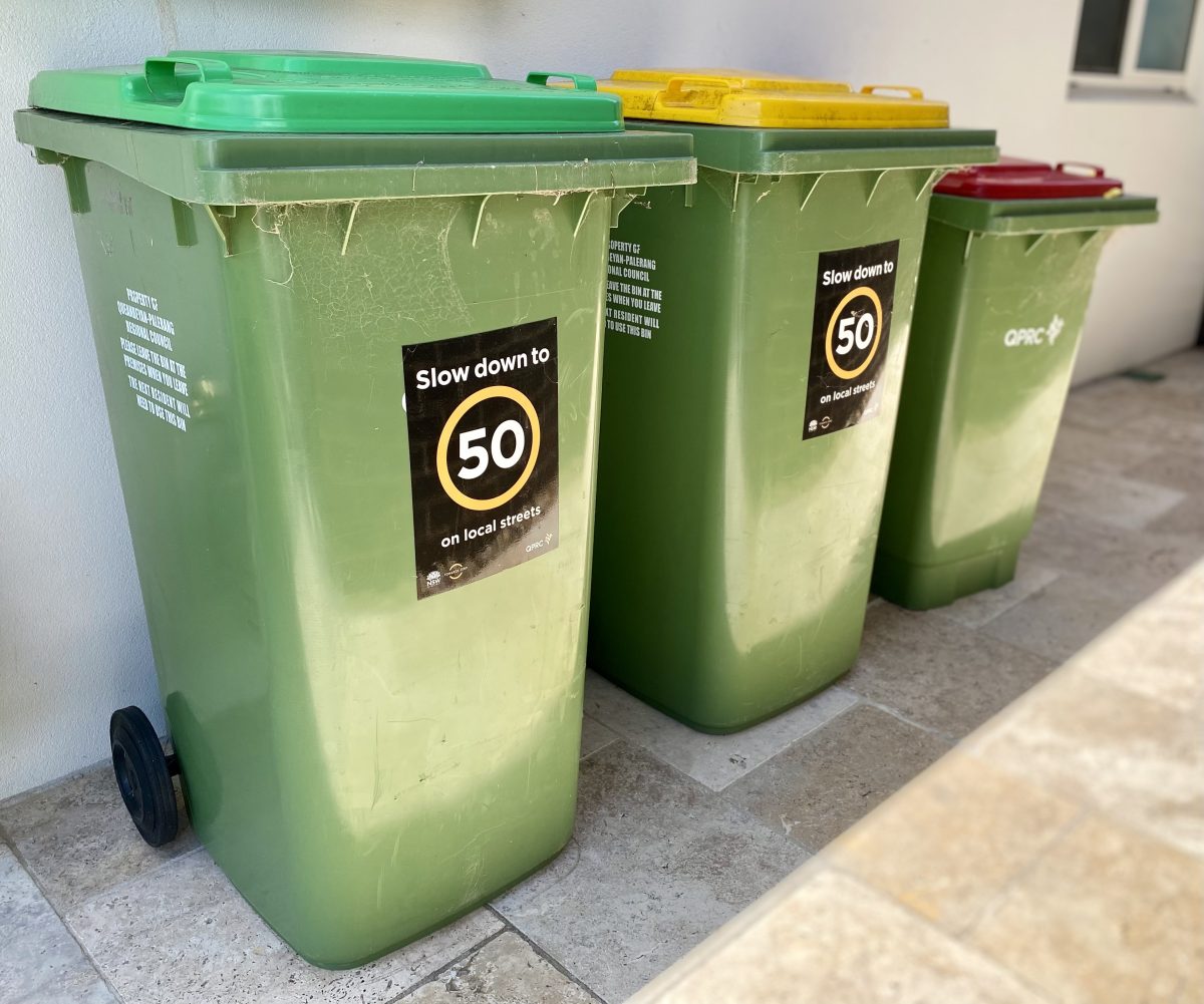 Green-, yellow- and red-lidded waste bins in a row