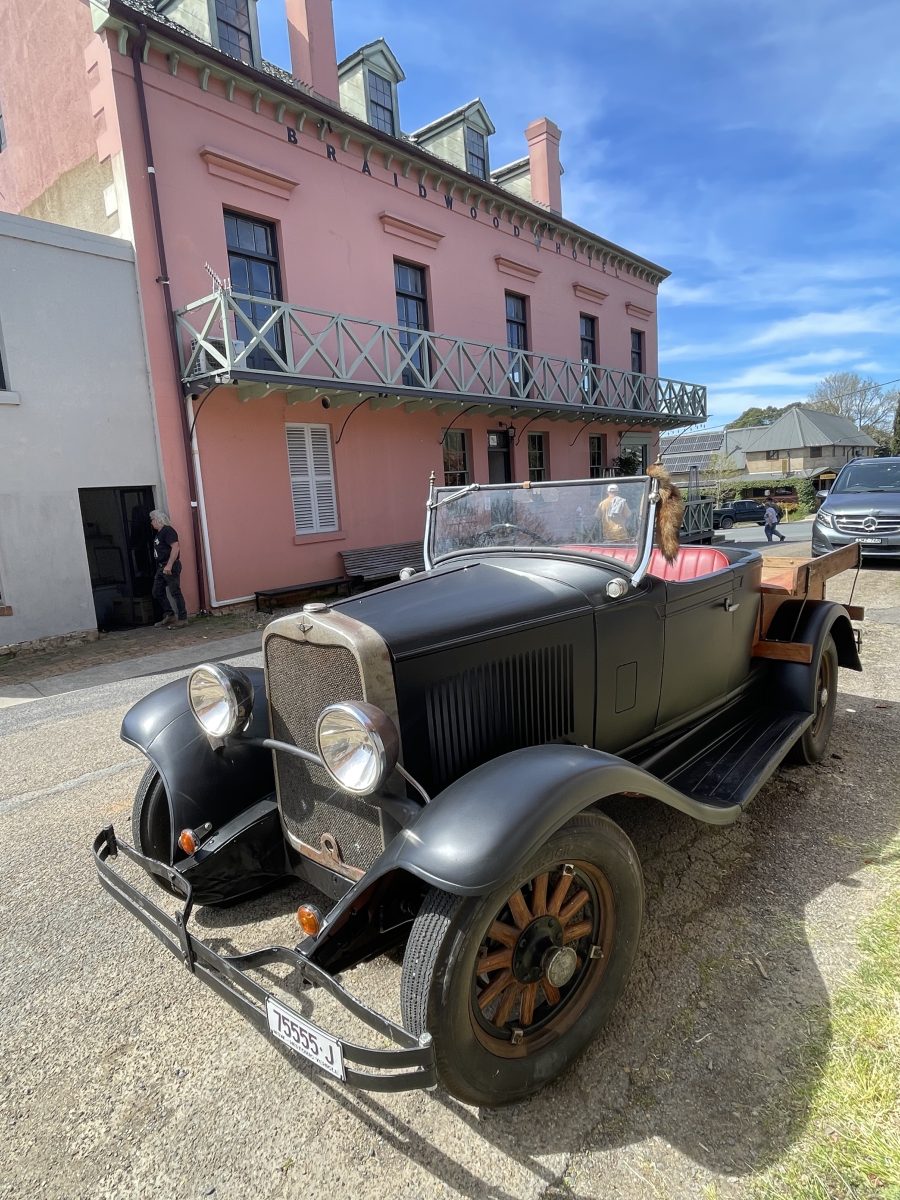 A restored 1930s car parked outside in the sun