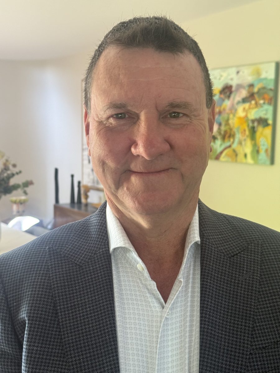 A smiling man in a suit jacket and white shirt
