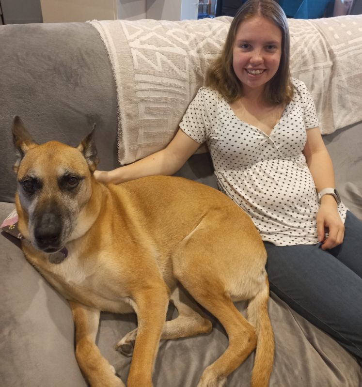 A smiling teenager with a dog, sitting on a couch