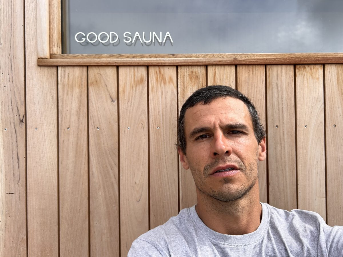 A man in a white shirt standing in front of a sauna