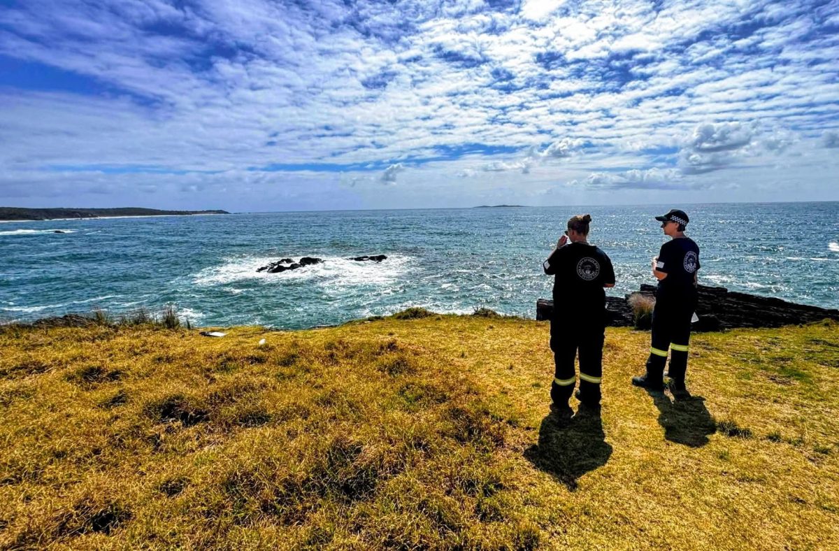 Two emergency service workers in uniform looking over a cliff