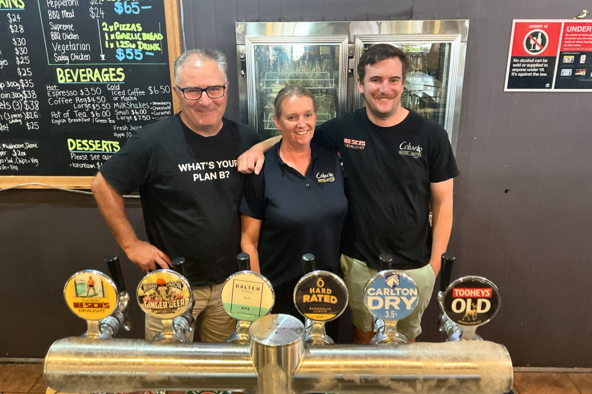 Three people standing behind a pub bar.