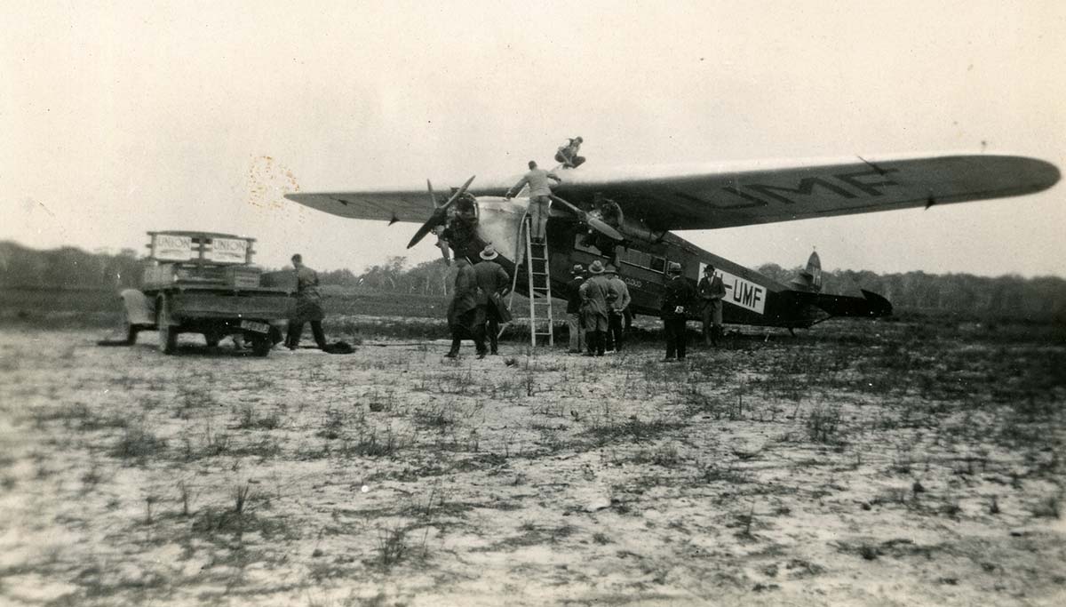 old photo of a plane, truck and several men