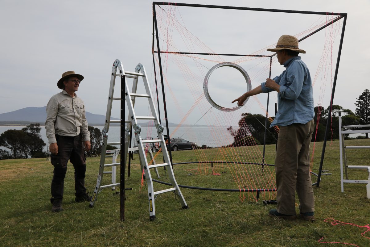 two men setting up an exhibition sculpture by the sea
