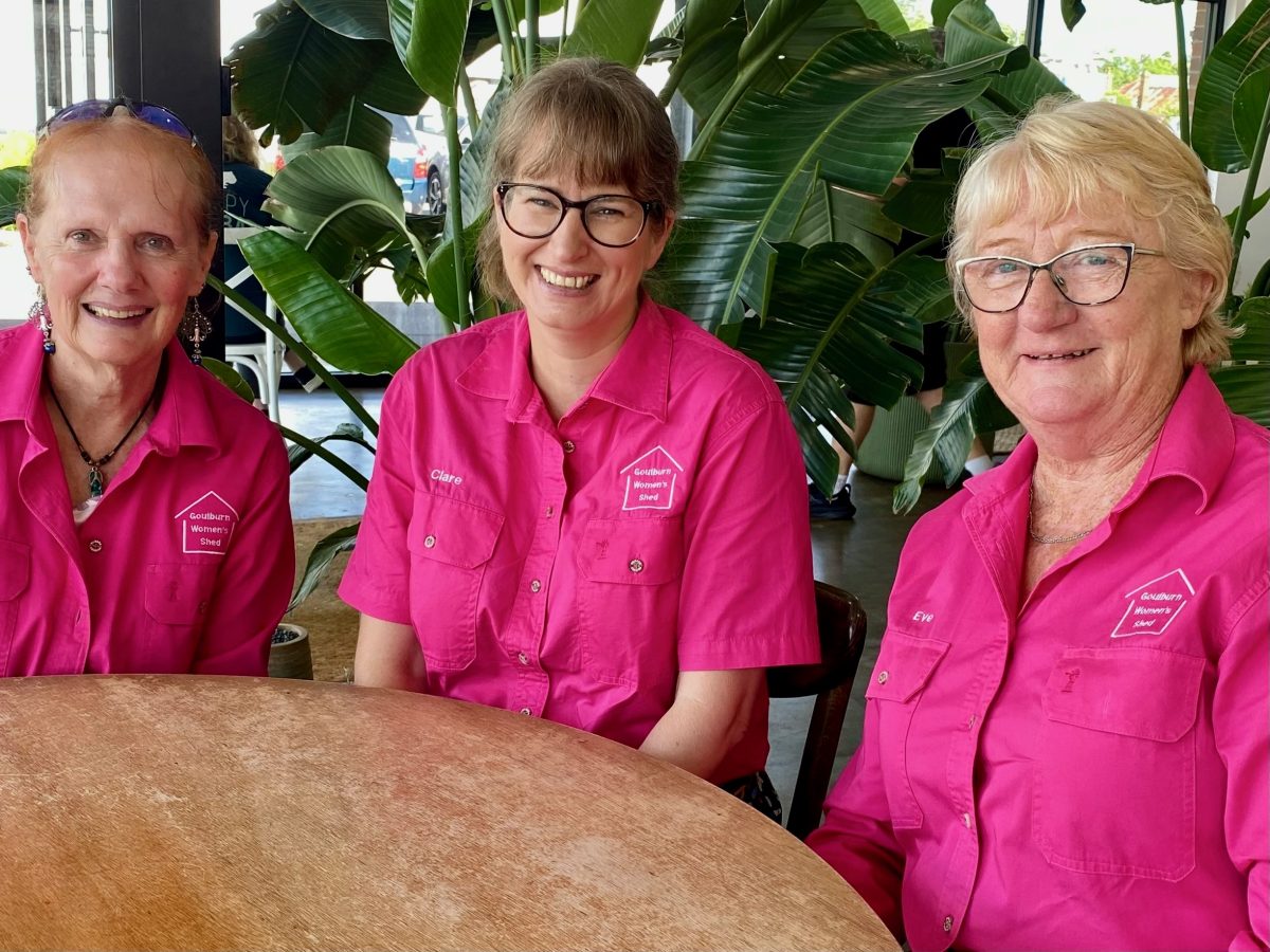 three women in pink shirts sitting around a table