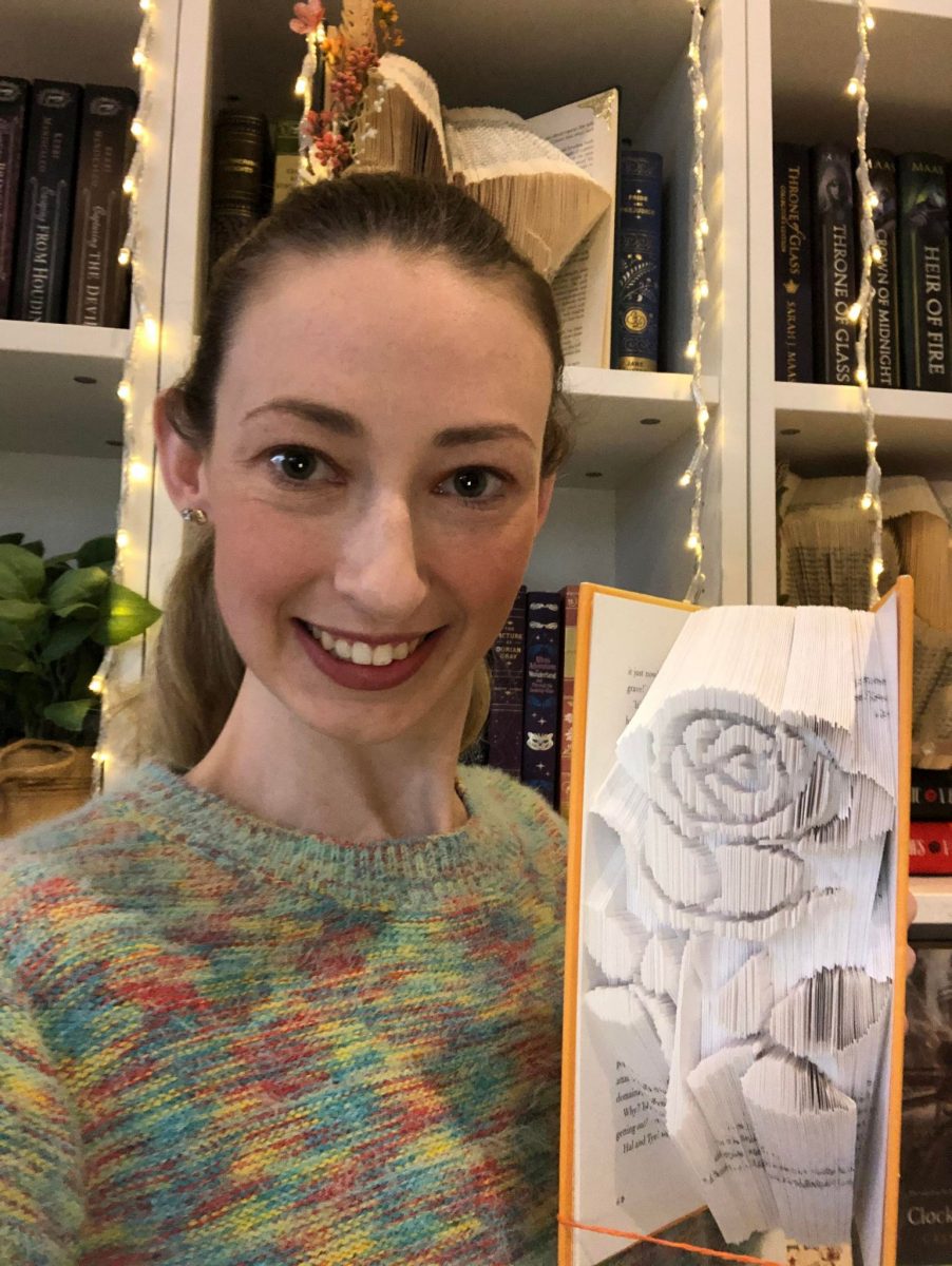 Woman holding book folded into sculpture of a rose